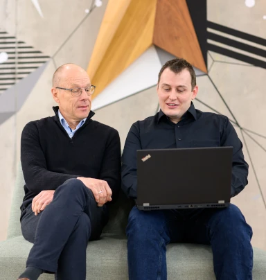 Thorsten sitzt mit einem Kunde vor einem Laptop und beschreibt das Vorgehen.